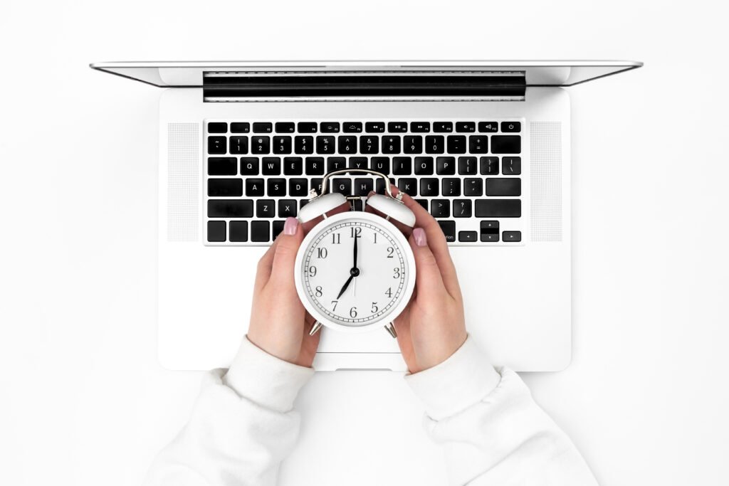 alarm clock female hands laptop white background top view